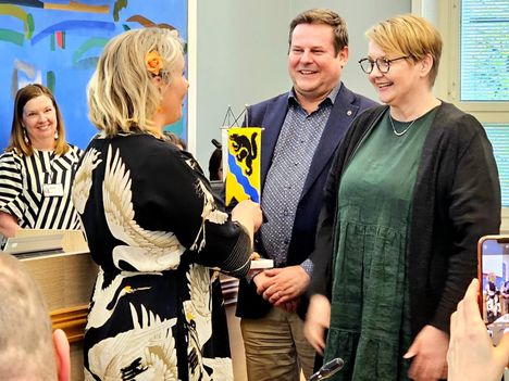 Maria Asunta (selin) sai Arja Laitiselta ja Jari Haapaniemeltä lahjaksi Nokia-viirin. Taustalla hallintojohtaja Hanna Vuojela.