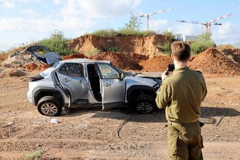 An Israeli soldier took pictures of a car damaged in a missile strike on Wednesday morning.