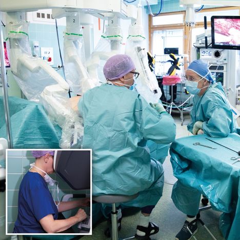 Robottiavusteisessa tyräleikkauksessa assistenttina toimiva yleiskirurgian ja gastroenterologisen kirurgian erikoislääkäri Mikko Ahtinen (vas.) ja instrumenttihoitaja Sirkku Harra keskustelevat potilaan ja nelikätisen leikkausrobotin vieressä. Oikealla leikkauksen kulkua seuraa valvoja hoitaja Nina Lähteenmäki.